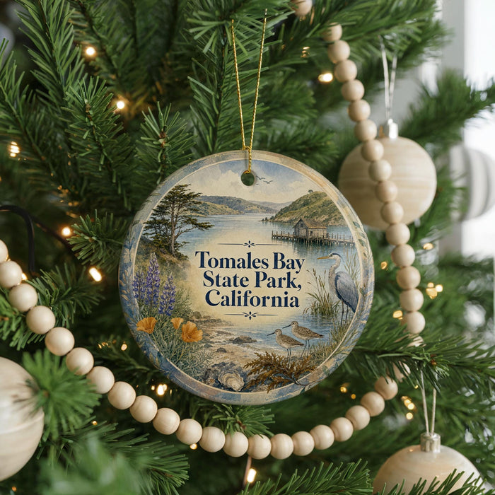 A round ornament hanging on a Christmas tree, featuring a scenic image of Tomales Bay State Park, California.