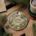 A decorative ornament featuring illustrations of Tomoka State Park in Florida, surrounded by pine branches and a cup of coffee on a wooden surface.