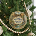 A round ornament hanging on a Christmas tree, featuring a desert landscape with a bridge and cacti.