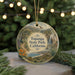 A decorative ornament featuring a scenic landscape with a waterfall, trees, and mountains, hanging from a string.