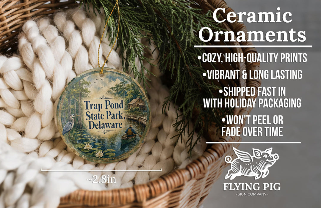 Ceramic ornaments, specifically a "Trap Pond State Park, Delaware" ornament, are displayed in a wicker basket. The ornament features a serene scene of a pond with a bird and a boat. The text highlights the ornament's features, such as being cozy, high-quality, vibrant, and long-lasting, and mentions that it is shipped fast in holiday packaging, won't peel or fade over time, and is available in a 2.8-inch size.