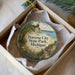 A round ornament with a scenic image of Traverse City, Michigan, featuring a beach, a boat, and a path leading to a cliff overlooking the water.