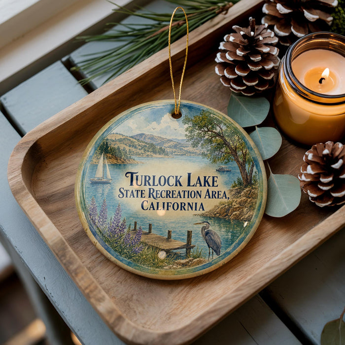A wooden tray with a decorative ornament featuring a scenic lake landscape, pine cones, and a lit candle.