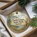 A decorative ornament in a box, featuring a scenic image of Tuttle Creek State Park in Kansas, with a bird, deer, and other natural elements.