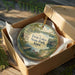 A decorative ornament in a wooden box, featuring a scenic landscape with a lake and trees, with the text "Twin Lakes State Park, Iowa" printed on it.
