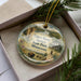 A decorative ornament in a box, featuring a scenic landscape with a teepee, buffalo, and other natural elements.