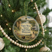 A round ornament hanging on a Christmas tree, featuring a scenic landscape with a river, mountains, and a teepee.