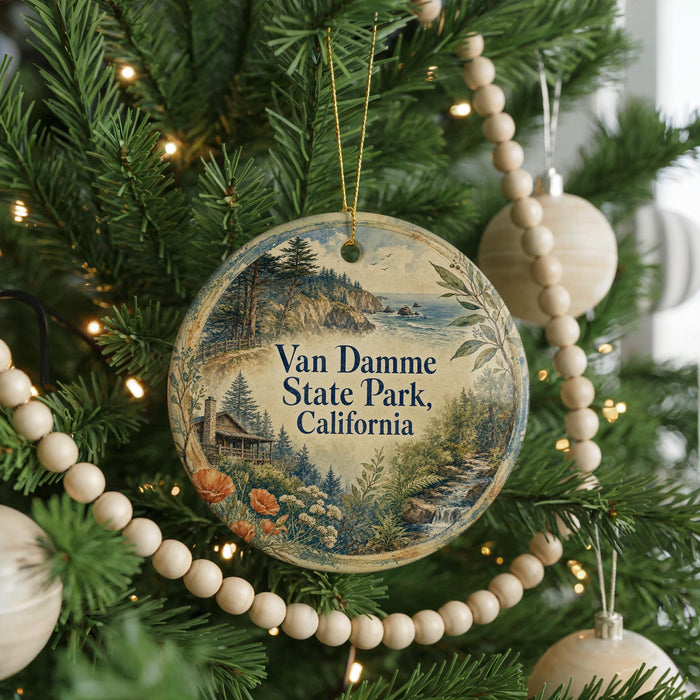 A round ornament hanging on a Christmas tree, featuring a scenic landscape with a house, trees, and a body of water.