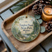 A decorative ornament with a scenic image of Vaughn Woods State Park, Maine, sits on a wooden tray alongside pine cones and a lit candle.