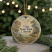 A round ornament with a scenic landscape of a mountain, river, and cabin, surrounded by greenery and twinkling lights.
