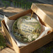 A decorative ornament in a box, featuring a scenic landscape of a river and trees, with the text "Village Creek State Park, Arkansas" printed on it.