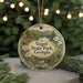 A round ornament with a scenic landscape of Vogel State Park, Georgia, featuring a river, mountains, and trees, is displayed on a table with pine branches and twinkling lights in the background.