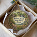 A decorative ornament in a box, featuring a scenic landscape with a river, waterfall, and various flora and fauna.