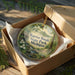 A decorative ornament in a brown box, featuring a scenic image of Warren Woods State Park in Michigan.