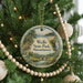A round ornament on a Christmas tree, featuring a scenic landscape with a waterfall and pine trees, with the text "Wells State Park, Massachusetts" displayed on it.