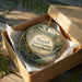 A decorative ornament in a box, featuring a scenic landscape of Wendell State Forest in Massachusetts.