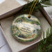 A decorative ornament with a scenic landscape of Western Gateway Heritage State Park in Massachusetts, featuring a train, a bridge, and a waterfall.