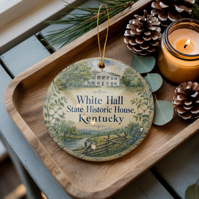 A decorative ornament featuring a house and trees, placed on a wooden tray next to a lit candle and pine cones.