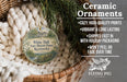 Ceramic ornaments, featuring a round ornament with a house design, are displayed in a basket with greenery.