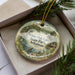 A decorative ornament in a box, featuring a scenic image of White Oak Lake State Park in Arkansas.