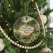 A round ornament hanging on a Christmas tree, featuring a scenic image of White Pines Forest State Park, Illinois.