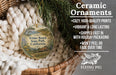 Ceramic ornaments, featuring a round ornament with a landscape scene and text, hanging from a wicker basket.