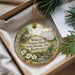 A decorative ornament in a box, featuring a painting of a historic house surrounded by flowers and greenery.