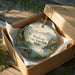 A decorative ornament in a box, featuring a scenic landscape of Winchester Lake State Park, Idaho.