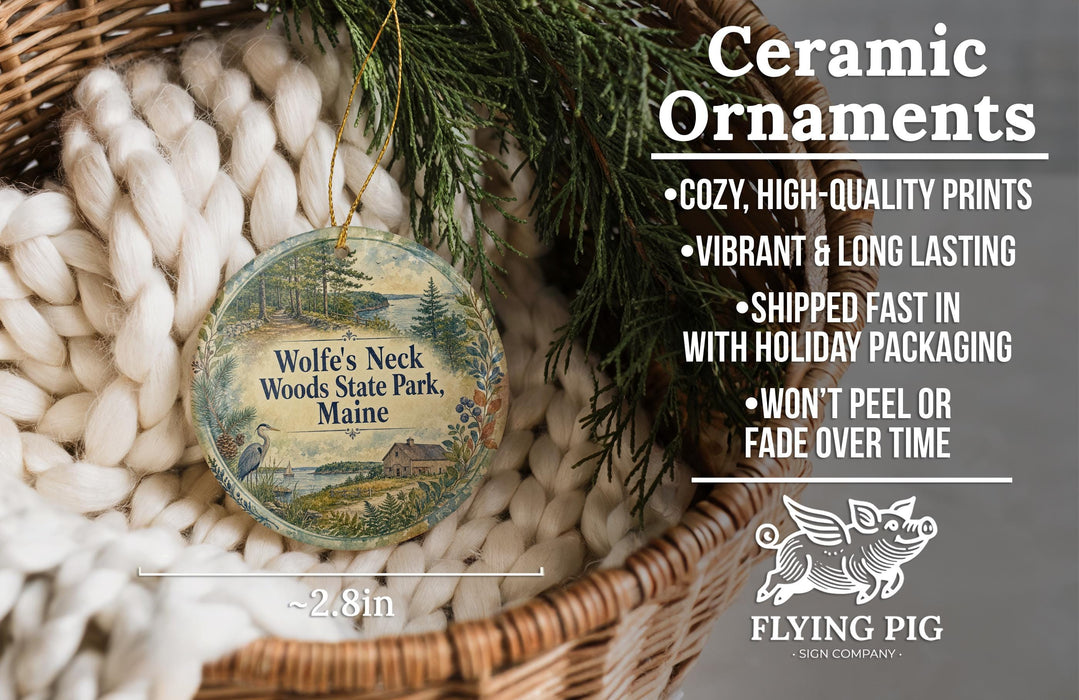 Ceramic ornaments, featuring a round ornament with a scenic landscape and text, are displayed in a basket with pine branches.