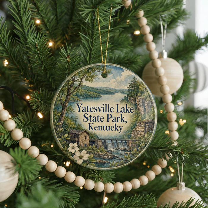 A round ornament hanging on a Christmas tree, featuring a scenic landscape with a lake and a waterfall.