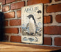 a poster of a penguin on a brick wall, with a wooden table below it.
