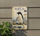 a penguin illustration on a wall, with a plant in the foreground.