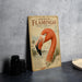 a vintage-style metal sign with an illustration of a flamingo, placed on a table next to some black camera lenses.