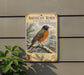 A vintage-style metal sign depicting an American robin in winter snow, mounted on a wall next to a plant.