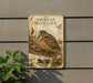 a vintage-style metal plaque with an illustration of a woodcock bird, mounted on a wall.