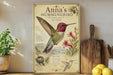 A framed illustration of a hummingbird, featuring detailed illustrations of the bird, flowers, and other elements, is displayed on a shelf next to a wooden cutting board and a potted plant.