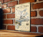A vintage-style metal sign with an illustration of a bird, mounted on a brick wall.