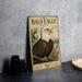 a vintage-style metal sign with an illustration of a bald eagle perched on a branch, surrounded by pine trees and mountains.