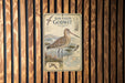 a vintage-style metal sign with a bird illustration, mounted on a wooden wall.