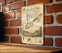 a vintage-style metal sign with an illustration of a barn owl in flight, mounted on a brick wall.