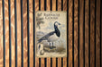 A vintage-style metal sign with a black and white illustration of a barnacle goose, mounted on a wooden wall.