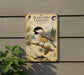 a vintage-style metal sign with a black-capped chickadee illustration, mounted on a wall next to a plant.