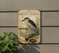 a vintage-style metal sign with a black-crowned night-heron illustration, mounted on a wall next to a plant.