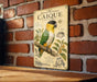 a vintage-style metal sign with a colorful illustration of a parrot, mounted on a brick wall.