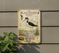 A vintage-style metal sign with illustrations of a black-necked stilt bird, a tall wading bird with long legs and a distinctive black and white plumage, standing in a shallow water body surrounded by plants.