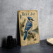A vintage-style poster of a blue jay bird is displayed on a wall, accompanied by a few black camera lenses.