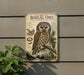 a vintage-style metal sign with an illustration of a Stryde's Boreal Owl, a species of owl native to North America. The sign is mounted on a gray wall, and there is a plant to the left of the sign.