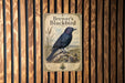 A vintage-style poster of a blackbird is displayed on a wooden wall.