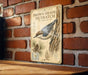 a vintage-style metal sign with illustrations and text, mounted on a brick wall.