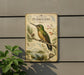 a vintage-style metal sign depicting a hummingbird perched on a branch, surrounded by various flora and fauna.